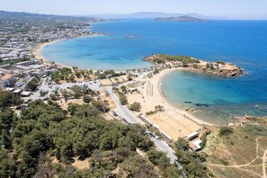 An aerial view of a coastal area with a beach, a small island, and a town with buildings and roads. - Villagioi III Pool Villa 250m to Sandy Beach (Chania)
