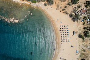 An aerial view of a beach with clear turquoise water, sandy shore, and several umbrellas and beach chairs. - Villagioi III Pool Villa 250m to Sandy Beach (Chania)