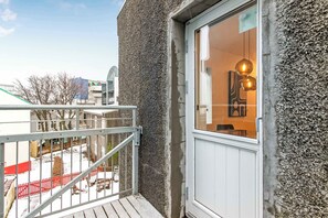 Ein Gebäude mit strukturierter Außenfassade, einem Balkon mit Metallgeländer und einem Fenster mit hängender Lampe.