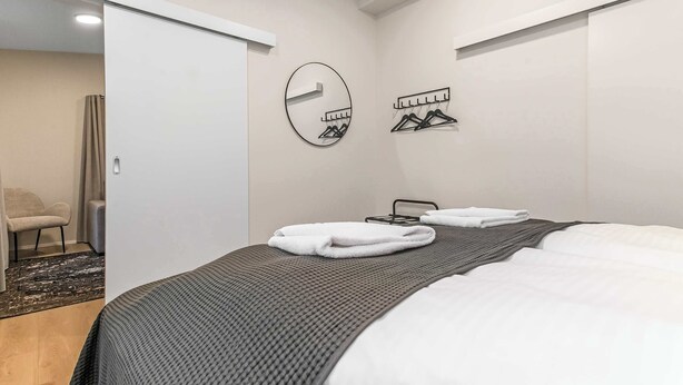 A bedroom with a bed, a mirror, and a coat rack. - TYS One Bedroom Apartments (Reykjavík)