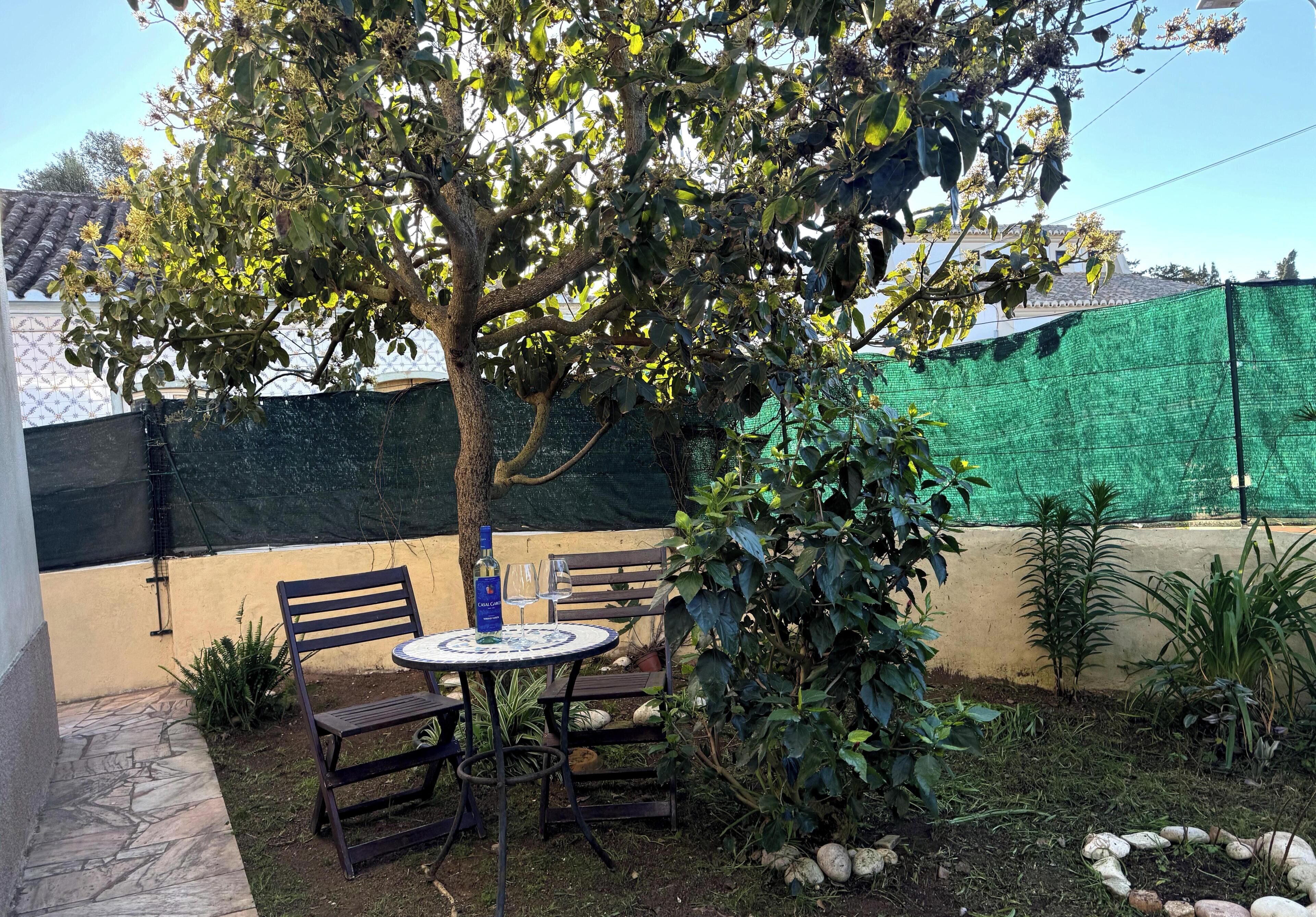 Eine Terrass mit Tisch, Stühlen und einem Baum.