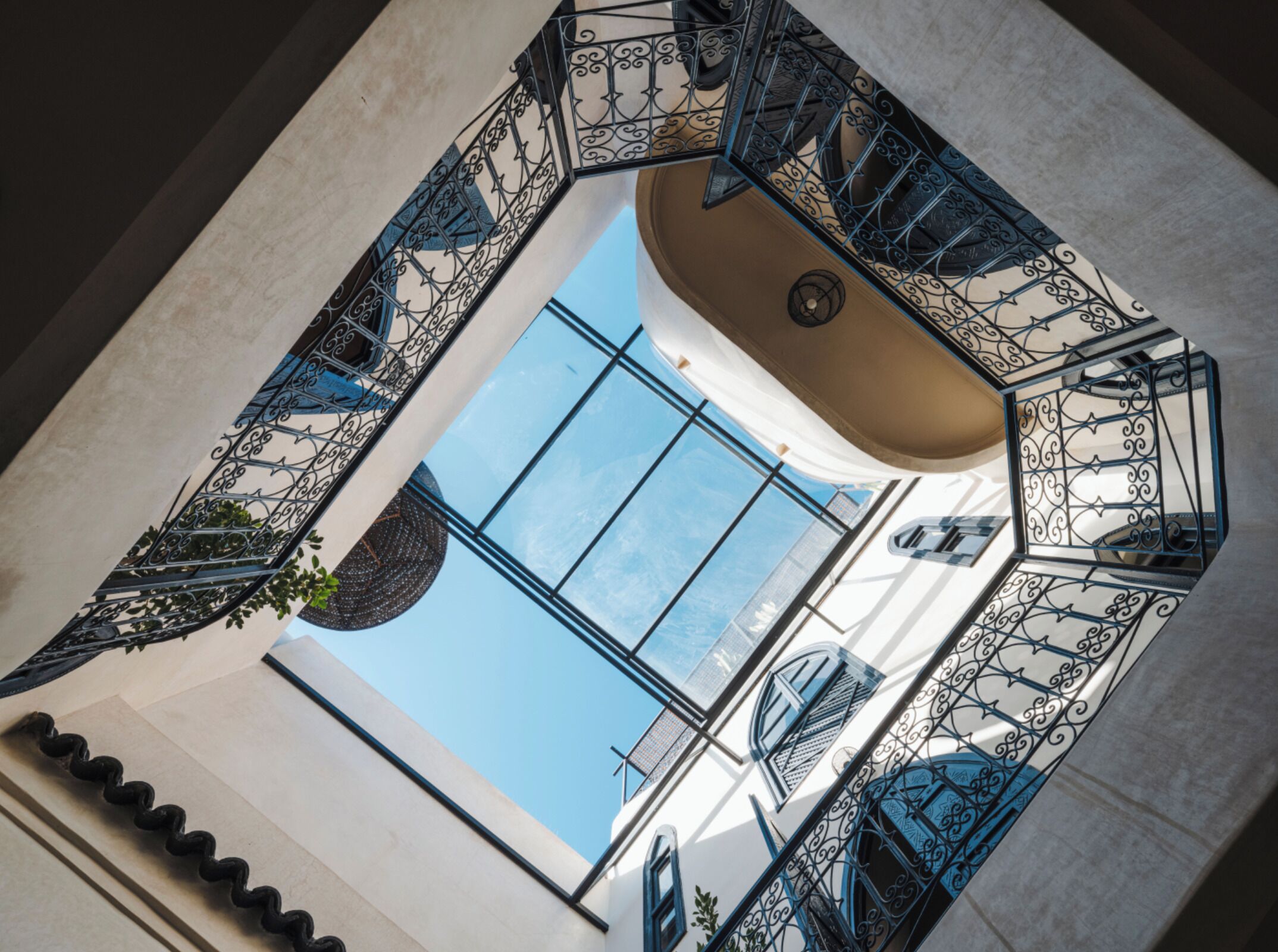 A spiral staircase with ornate metal railings, a large window, and a view of the sky.