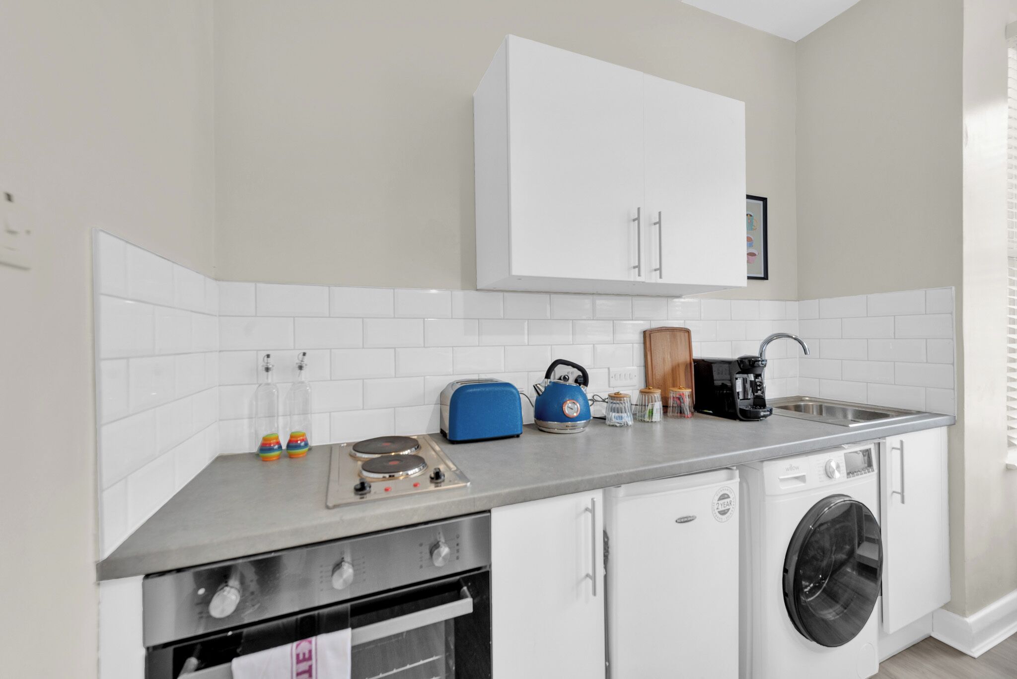 A compact kitchen with a stove, oven, washing machine, and a microwave.
