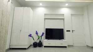 Un salon moderne doté d’un téléviseur à écran plat, de meubles blancs et de vases décoratifs.