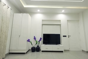 A modern living room with a flat-screen TV, white cabinetry, and decorative vases.