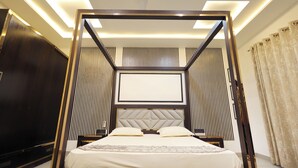 Un lit à baldaquin avec une tête de lit capitonnée, un téléviseur à écran plat et une table de chevet avec une lampe.