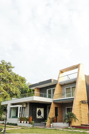 A modern two-story house with a balcony, large windows, and a front entrance with steps.