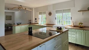 Una cocina moderna con una isla central, armarios verde claro y encimera de madera.