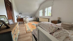 A bedroom with a bed, a desk, a chair, a radiator, and a window. - Casa Santi - 10 Min de Santiago  (Santiago de Compostela)