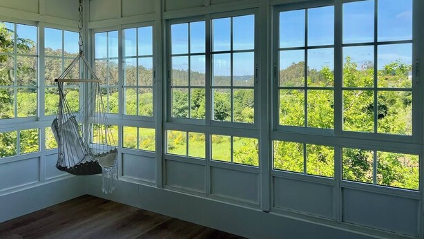 Una habitación con ventanas amplias, una silla colgante y vistas a zonas verdes.