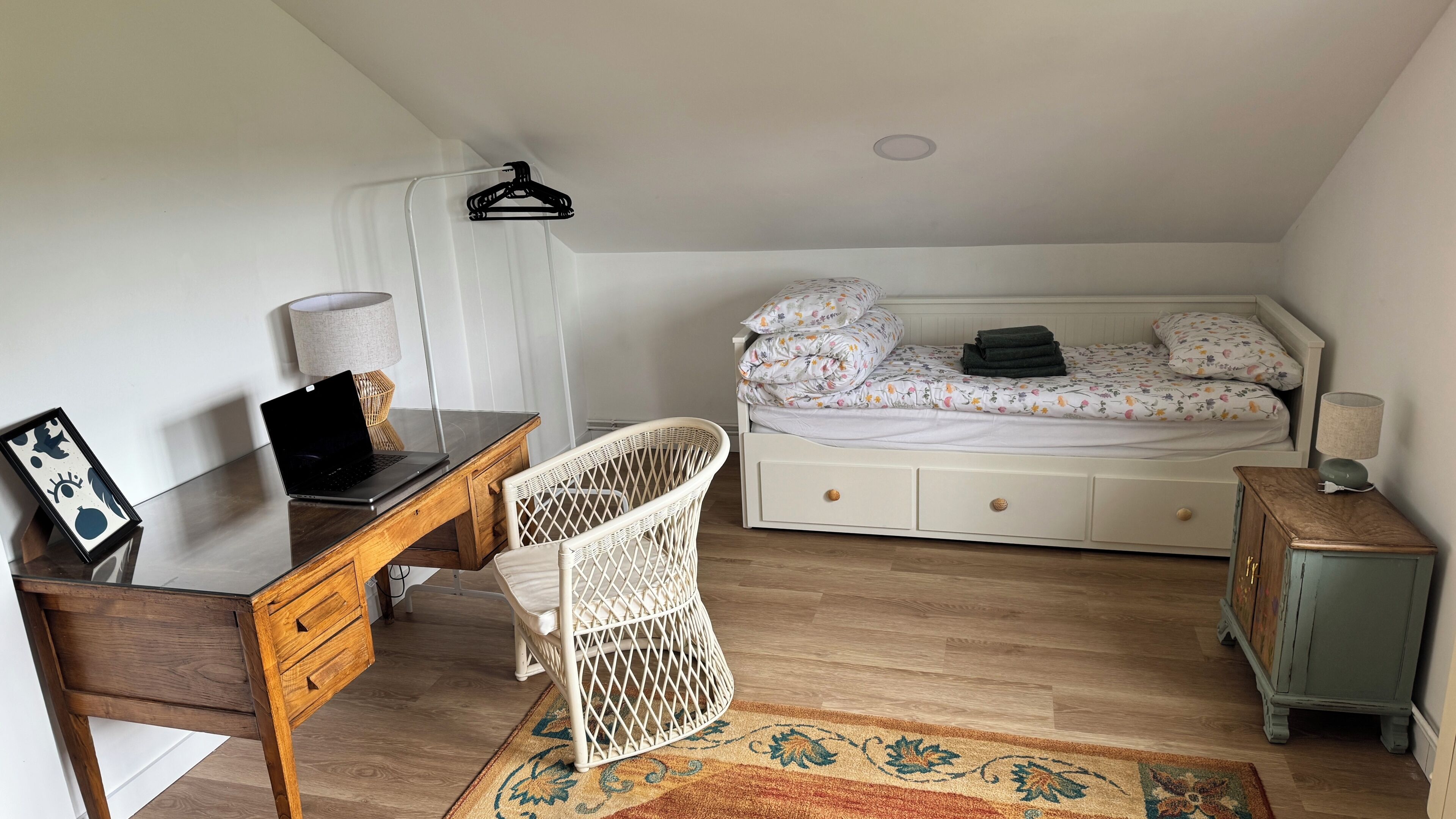 Une chambre à coucher comprenant un lit, un bureau, une chaise, une lampe et un petit meuble.
