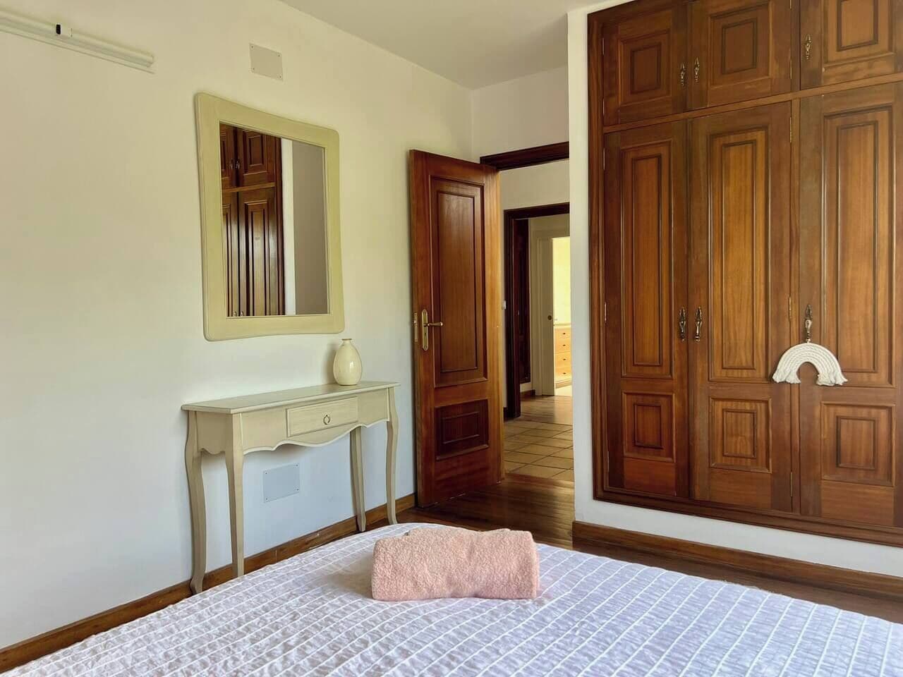 A bedroom with a bed, a bedside table, a mirror, and a wardrobe.