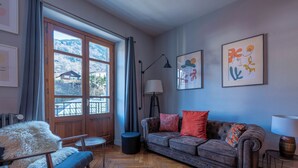 A room with a herringbone floor, a sofa, a chair, a lamp, and two framed artworks on the wall. - Saint Gervais 2 bed apart. Sleeps upto 6, Chic Period Building Central location (Saint-Gervais-les-Bains)