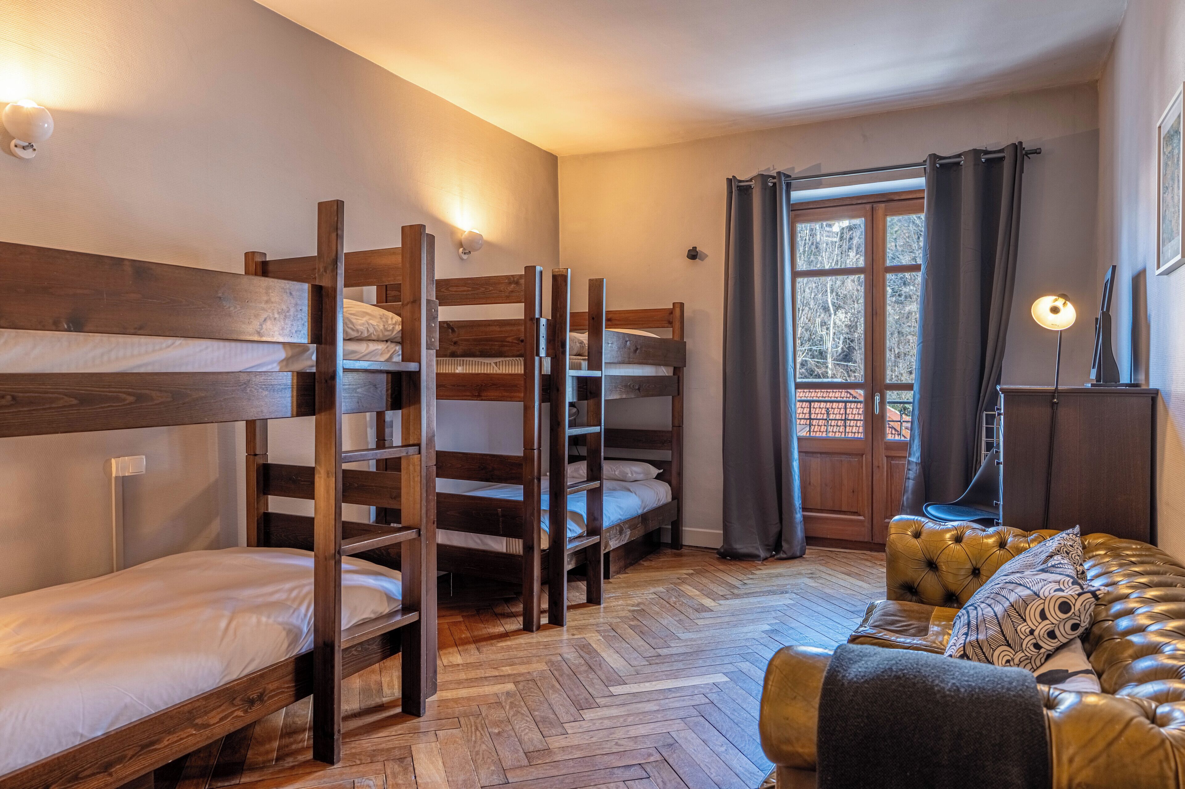 Habitación con literas, un sofá y una ventana con cortinas.
