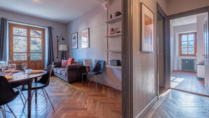 A room with a dining table set, a sofa, a chair, a lamp, and a radiator. - Saint Gervais 2 bed apart. Sleeps upto 6, Chic Period Building Central location (Saint-Gervais-les-Bains)