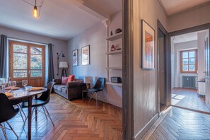 A room with a dining table set, a sofa, a chair, a lamp, and a radiator. - Saint Gervais 2 bed apart. Sleeps upto 6, Chic Period Building Central location (Saint-Gervais-les-Bains)