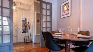A dining area with a table set for four, glasses, plates, and a ladder leaning against the wall. - Saint Gervais 2 bed apart. Sleeps upto 6, Chic Period Building Central location (Saint-Gervais-les-Bains)