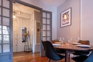 A dining area with a table set for four, glasses, plates, and a ladder leaning against the wall. - Saint Gervais 2 bed apart. Sleeps upto 6, Chic Period Building Central location (Saint-Gervais-les-Bains)