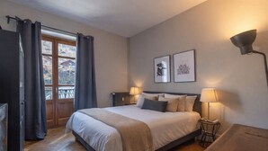A bedroom with a bed, two bedside lamps, a radiator, and two framed pictures on the wall. - Saint Gervais 2 bed apart. Sleeps upto 6, Chic Period Building Central location (Saint-Gervais-les-Bains)
