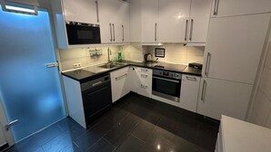 Una cucina moderna con mobili bianchi, un piano di lavoro nero, lavastoviglie, forno e microonde.