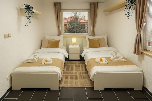 A twin room with two beds, a small bedside table, a nightstand, a window with curtains, and a view of a building outside.