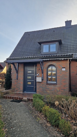 A brick house with a dark blue door, a small window, and a number '48' sign.