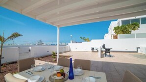 Un área de comedor en la azotea con una mesa lista para cuatro personas, asientos exteriores y vistas del horizonte de la ciudad.