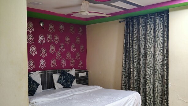 Una camera da letto con un letto, una ventola a soffitto, tende a motivi decorativi e una testiera.