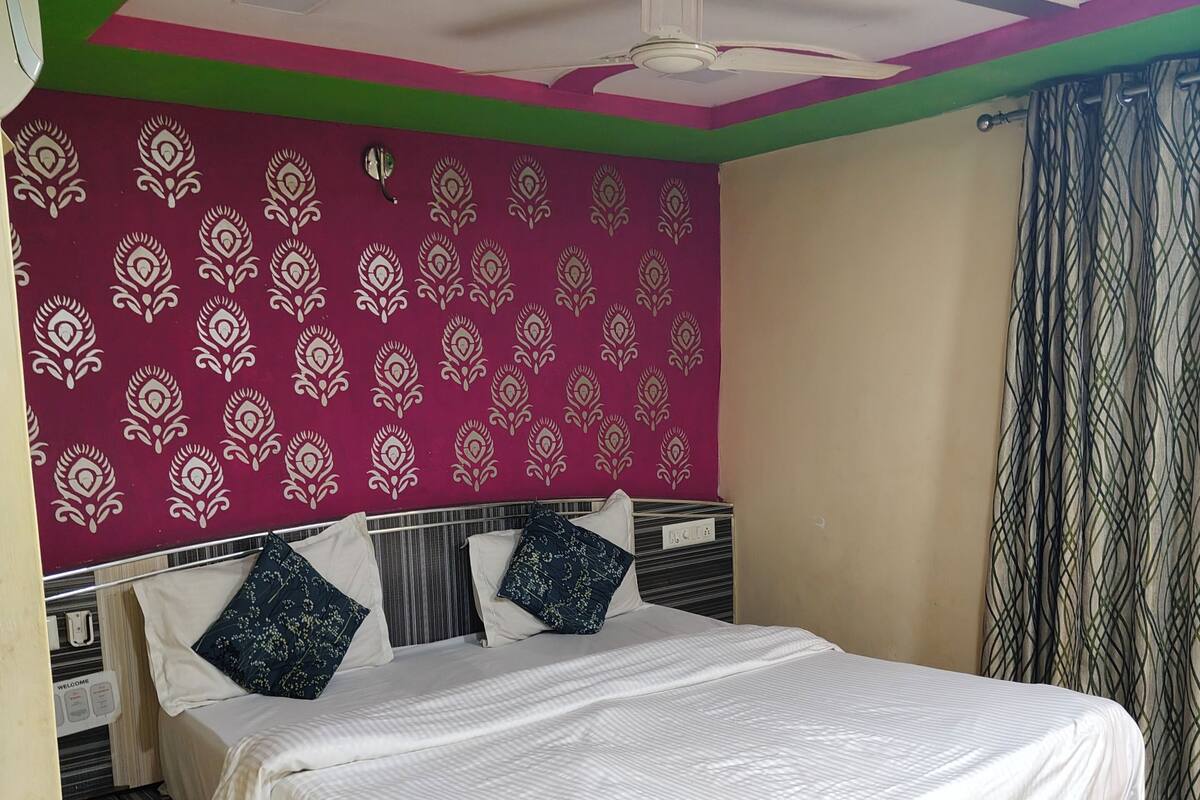 A neatly made bed with a white bedspread, a headboard with a patterned design, and a ceiling fan.