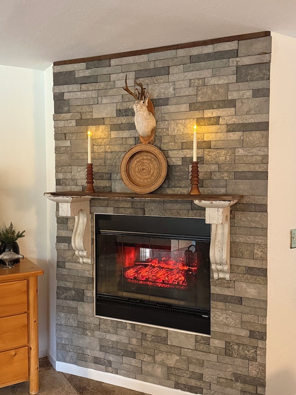 A fireplace with a stone wall, two candles, and a decorative plate.