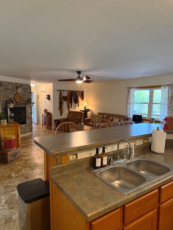 A kitchen with a central island, a fireplace, and a dining area with a sofa and chairs.