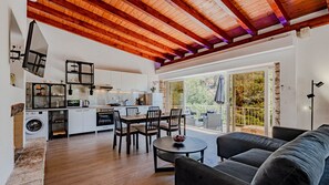 A spacious living area with a dining table, sofa, and a kitchen with a built-in oven and washing machine. - Beach Escape Lujo by Villas Guide (Vela Luka)