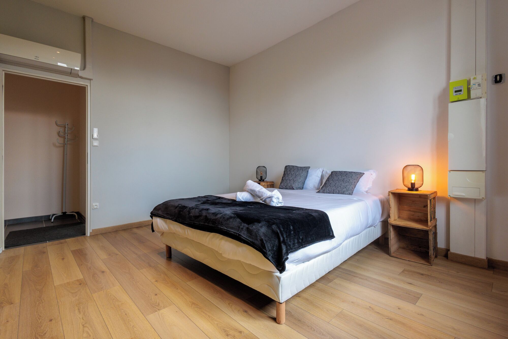Ein Schlafzimmer mit Bett, Nachttisch, Lampe und Kleiderschrank.