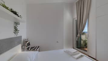 A modern hotel room with a bed, a window with curtains, a small table, and a chair.