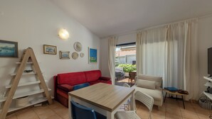 A furnished living room with a wooden table, two sofas, a TV, and a balcony with plants. - Punta Debij Apartments (Punat)