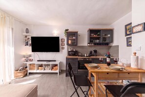Eine moderne Küche mit Flachbildfernseher, Holzschränken und einem Essbereich mit Tisch und Stühlen.