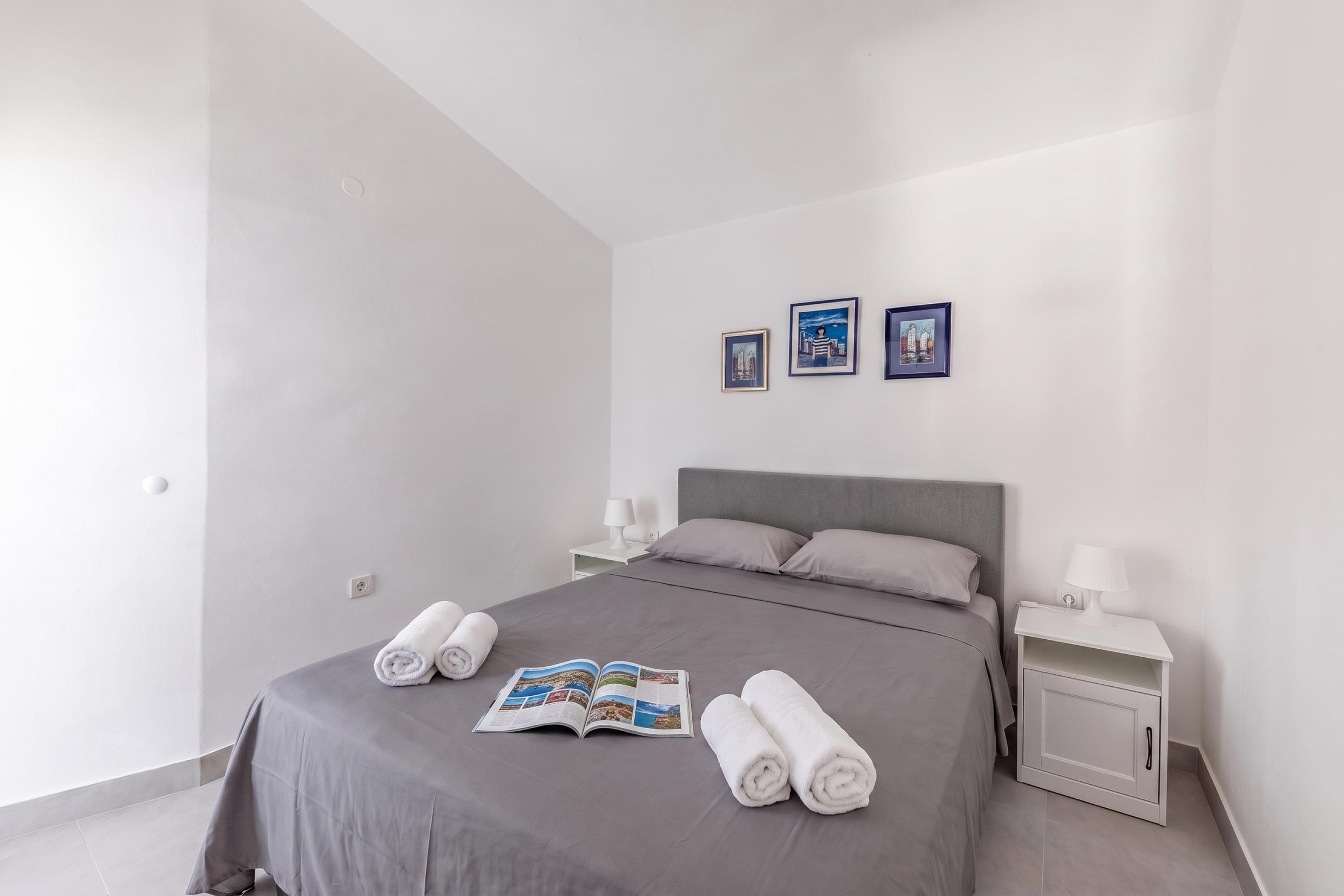 Una habitación de hotel moderna con una cama grande, dos mesitas de noche y una pared con tres cuadros enmarcados.