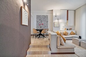 Ein modernes Wohnzimmer mit einer Couch, einem Esstisch mit Stühlen und einer Treppe zu einer weiteren Ebene.