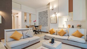 Una sala de estar moderna con un conjunto de sofás, una mesa de centro y un panel decorativo en la pared.