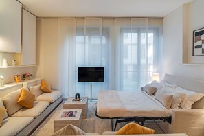Ein modernes Hotelzimmer mit Sofa, Bett, Fernseher und Nachttisch.