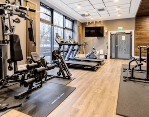 A gym with cardio equipment, weight machines, and a large window. - Art Deco Mokotów Suites - Parking & Gym by Downtown Apartments (Warszawa)
