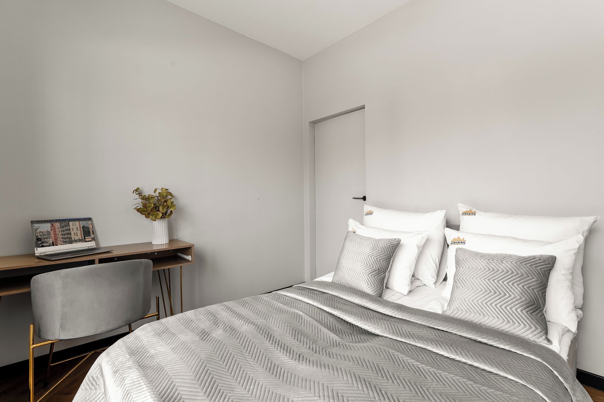 Un dormitorio con una cama, un escritorio, una silla y un estante en la pared.