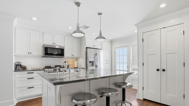 A modern kitchen with white cabinets, stainless steel appliances, and a central island with stools. - Midtown 3-bedroom house in vibrant Tulsa close to TU, Downtown, EXPO Square (Tulsa)