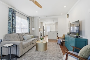 A modern living room with a sofa, coffee table, and a teal cabinet. - Midtown 3-bedroom house in vibrant Tulsa close to TU, Downtown, EXPO Square (Tulsa)