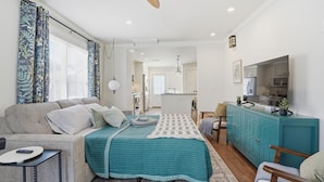 A modern living room with a sofa, a teal bedspread, a dining area, and a kitchen. - Midtown 3-bedroom house in vibrant Tulsa close to TU, Downtown, EXPO Square (Tulsa)