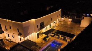 A modern building with a swimming pool, outdoor seating, and a well-lit patio area. - The Zeal Luxury Apartment  (Benin City)