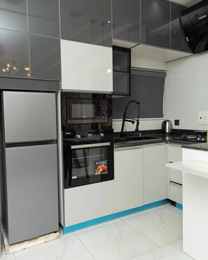 Una cocina moderna con refrigerador, microondas, horno y lavabo.