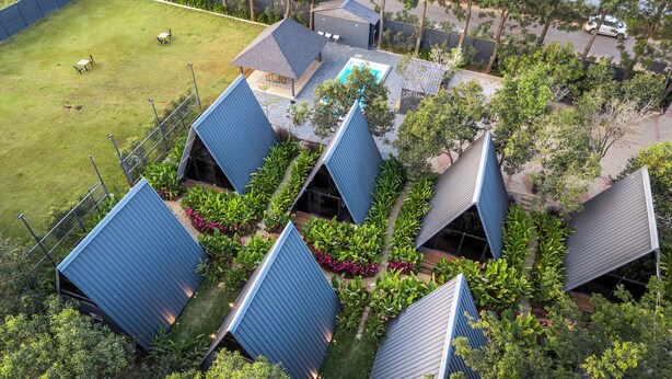 Un ensemble résidentiel comprenant plusieurs bâtiments aux toits bleus, une piscine et de nombreux espaces verts.