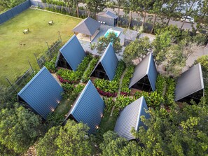 A residential complex with multiple blue-roofed structures, a swimming pool, and surrounding greenery. - Alaya Stays Inara Retreat Cottage (Bengaluru)