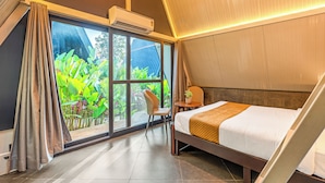 Une chambre à coucher avec un lit, une chaise, une petite table et une fenêtre avec des rideaux.